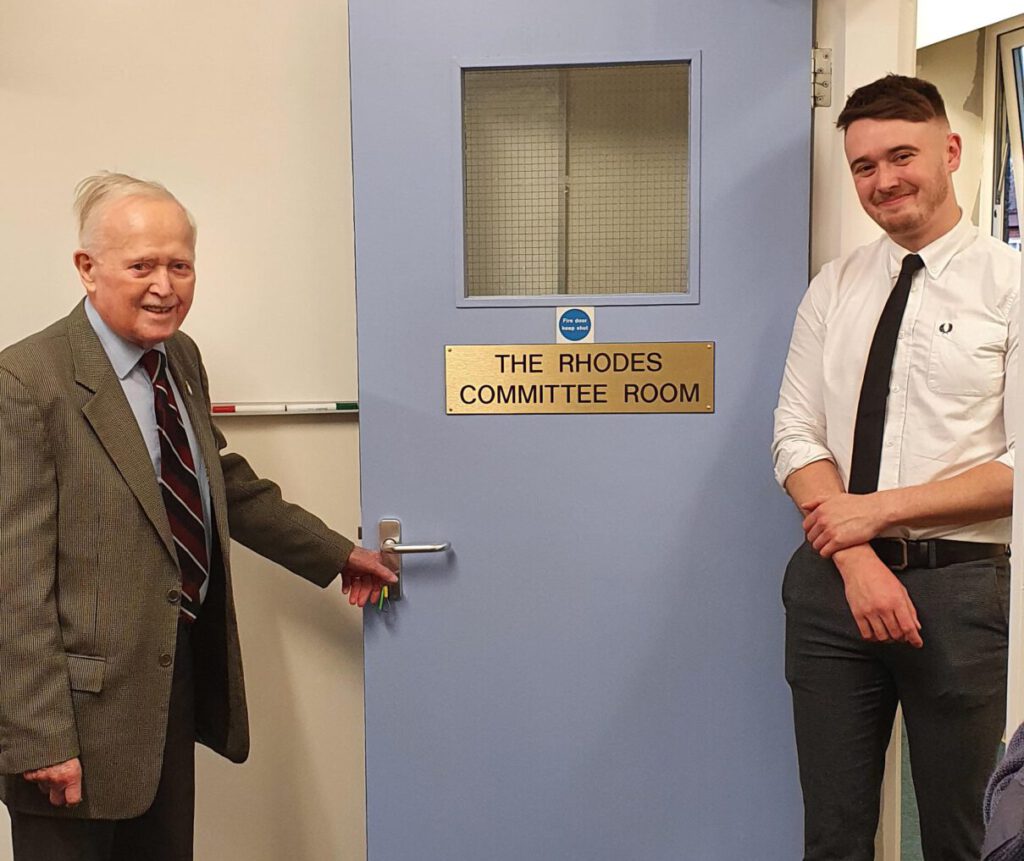 Don Rhodes stood with his grandson in front of the door to The Rhodes Committee Room